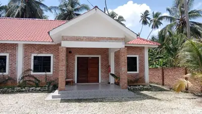 a brick house with a brown door and palm trees at As Sufi Villa in Kampung Sungai Air Tawar