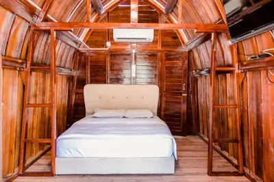 a bed in a room with wooden walls at As Sufi Villa in Kampung Sungai Air Tawar