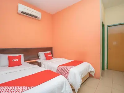 two beds in a room with orange walls at Hotel The Island in Pangkor