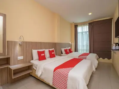 two beds in a hotel room with red pillows at Hotel The Island in Pangkor