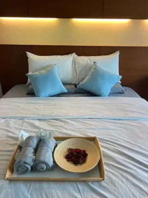a tray with towels and a plate of food on a bed at 2Beds Seaview Straits Quay comes with Carpark and Hothub in Bagan Jermal