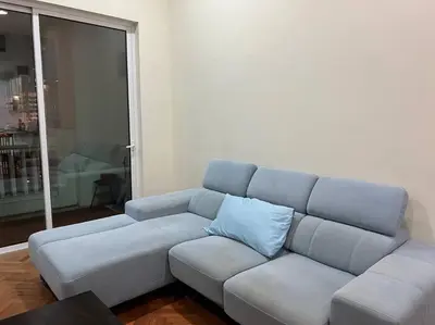 a couch in a living room with a blue pillow at 2Beds Seaview Straits Quay comes with Carpark and Hothub in Bagan Jermal