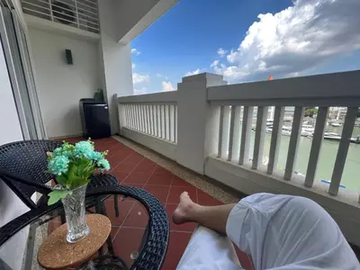a person laying on a balcony with a vase of flowers at 2Beds Seaview Straits Quay comes with Carpark and Hothub in Bagan Jermal