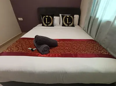 a bed with a black hat and a towel on it at L Ferringhi Hotel in Batu Ferringhi