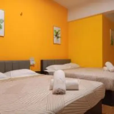 two beds in a room with yellow walls at Sabai Sabai Guesthouse in Bayan Lepas in Bayan Lepas