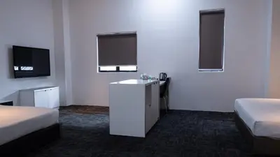 a room with two beds and a sink and a tv at Beverly Hotel in Taiping