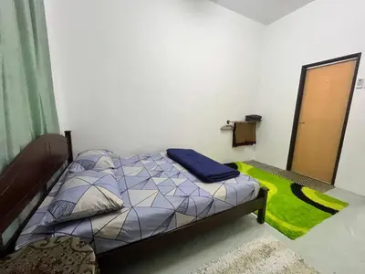 a bedroom with a bed and a green rug at Tapak 173 by Sutera Hōmes in Sungai Petani