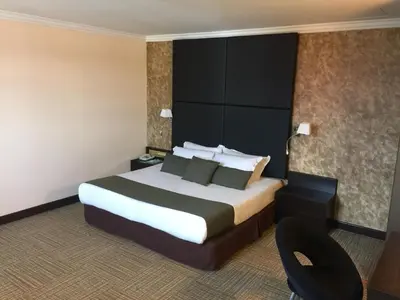 a hotel room with a large bed and a chair at Legend Inn Taiping in Taiping