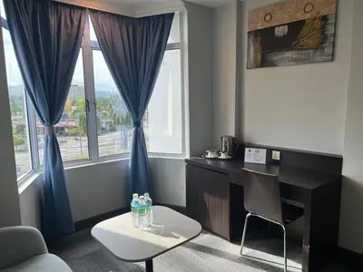 a room with a desk and a chair and windows at Legend Inn Taiping in Taiping