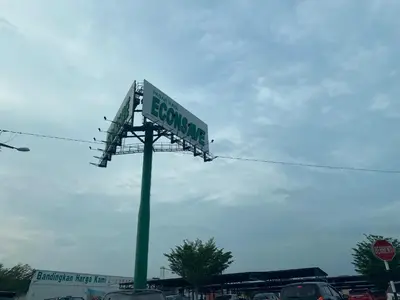 a green street sign on a pole in a parking lot at Jom singgah in Seri Iskandar