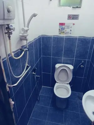 a blue tiled bathroom with a toilet and a sink at Hotel Muallim Tanjung Malim in Tanjung Malim