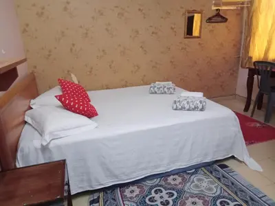 a white bed with red and white pillows on it at Hotel Muallim Tanjung Malim in Tanjung Malim