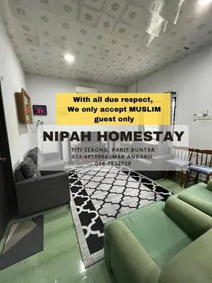 a living room with a couch and a sign on the wall at Nipah Homestay Parit Buntar in Parit Buntar