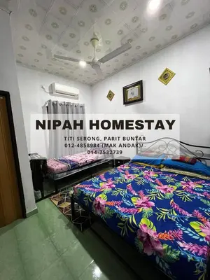 a bed in a room with a sign on the wall at Nipah Homestay Parit Buntar in Parit Buntar
