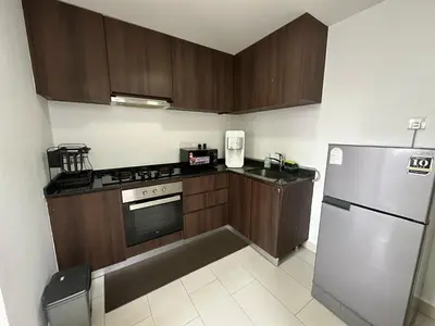 a kitchen with wooden cabinets and a stainless steel refrigerator at NEW 4Queen Bed 3 Room 2CP near Gurney with tvbox and KTV Set in Tanjong Tokong