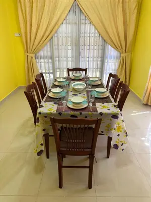 a dining room table with chairs and a tablecloth with flowers at GS HOMESTAY WHOLE VILLA in Bayan Lepas