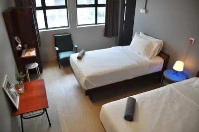 a room with two beds and a table and a chair at GRAYHAUS INN Ipoh in Ipoh
