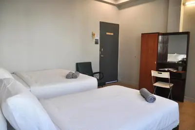 a room with two beds and a desk with a mirror at GRAYHAUS INN Ipoh in Ipoh