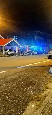 a gas station at night with cars parked in a parking lot at Kurnia Homestay in Slim River