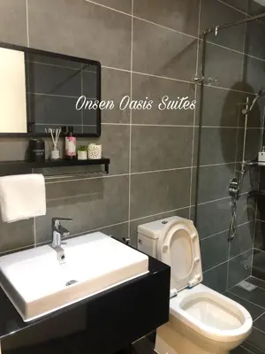 a bathroom with a sink and a toilet and a mirror at Onsen Oasis Premium Suites in Tambun