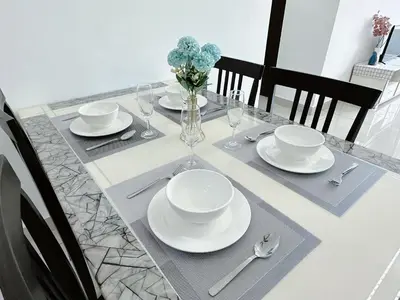 a table with plates and glasses and a vase with flowers at Ipoh Town - Majestic Cozy Deluxe Homestay in Ipoh