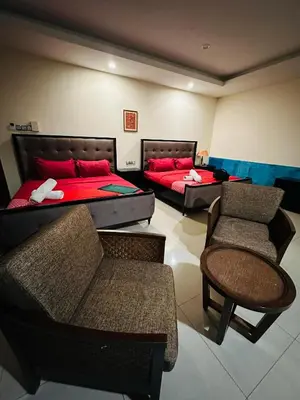 two beds in a room with chairs and tables at Maxwell inn in Taiping