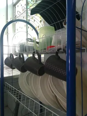 a bunch of dishes are sitting in a shelf at Homestay siti in Padang Serai