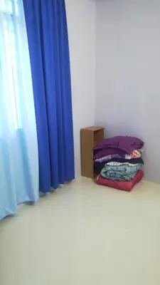 a room with a bed next to a blue curtain at Homestay siti in Padang Serai