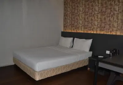 a bed with white sheets and pillows in a room at Merge Summit by Secoms in Teluk Intan