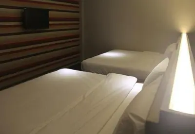 a bedroom with two beds and a tv on the wall at Merge Summit by Secoms in Teluk Intan