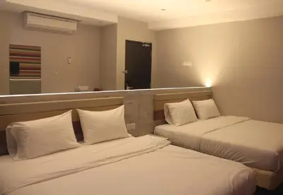 a hotel room with two beds and a mirror at Merge Summit by Secoms in Teluk Intan