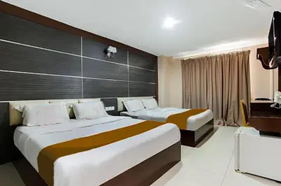 a hotel room with two beds and a television at Sejati Hotel in Sitiawan