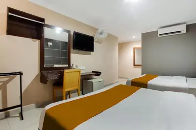 a hotel room with two beds and a desk and a tv at Sejati Hotel in Sitiawan