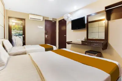 a hotel room with two beds and a television at Sejati Hotel in Sitiawan