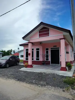 a pink house with a car parked in the driveway at Rizki Homestay Nibong Tebal in Nibung Tebal