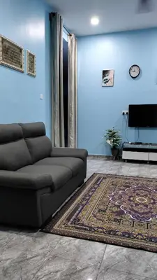 a living room with a couch and a blue wall at Rizki Homestay Nibong Tebal in Nibung Tebal