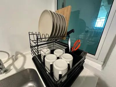 a dish drying rack with cups and a mirror on a sink at The Majestic-Loft De Tel in Ipoh