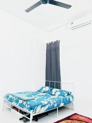a bed in a white room with a ceiling fan at D' Splash Garden Homestay in Baling