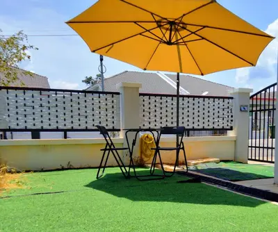 a table and two chairs under an umbrella at D' Splash Garden Homestay in Baling