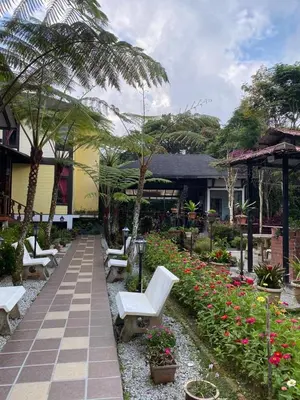 a garden with white chairs and flowers and a building at Cahaya Villa in Tanah Rata