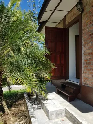 a porch of a house with a bench and palm trees at D'Impiana Riverview Chalet # Lenggong in Kampong Ulu Jepai