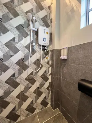 a shower in a bathroom with a tiled floor at Inn Homestay 2nd Floor Jasmine and Lavender unit in Teluk Intan