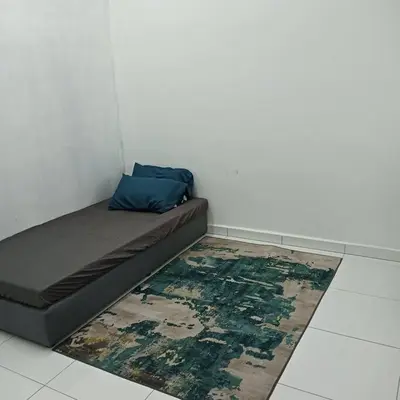 a bed in a room with a rug on the floor at Damai Homestay in Kepala Batas