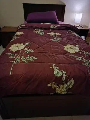 a bed with a red comforter with flowers on it at Sofea Inn Bukit Merah - Laketown A6172 in Kampong Selemat
