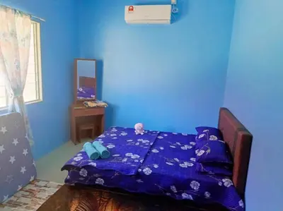 a blue bedroom with a bed with a blue wall at Teratak Desa Umaira in Tanjung Karang