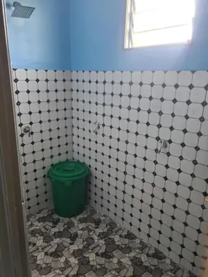 a bathroom with a green bucket in a white tiled wall at Teratak Desa Umaira in Tanjung Karang