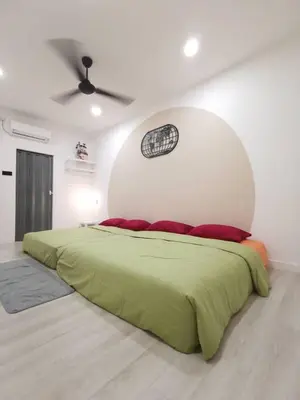 a bedroom with a green bed with a white wall at Wellson Home Ipoh 6 (15px+)\u6e29\u99a8\u8212\u9002\u5976\u6cb9\u98ce\u6c11\u5bbf15\u4eba in Ipoh