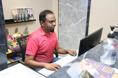 a man sitting at a desk with a laptop computer at Capital O 90897 Island City Hotel in George Town