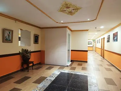 a hallway with orange and white walls and a table at Capital O 90897 Island City Hotel in George Town