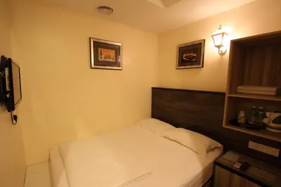 a bedroom with a white bed with a wooden headboard at Shamrock Guest House in Ipoh